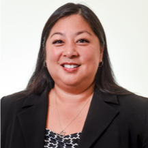 woman with long dark hair wearing a blazer and smiling